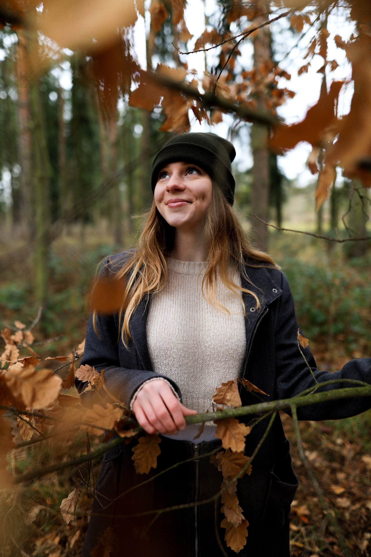 Young woman smiling among autumn leaves in the forest