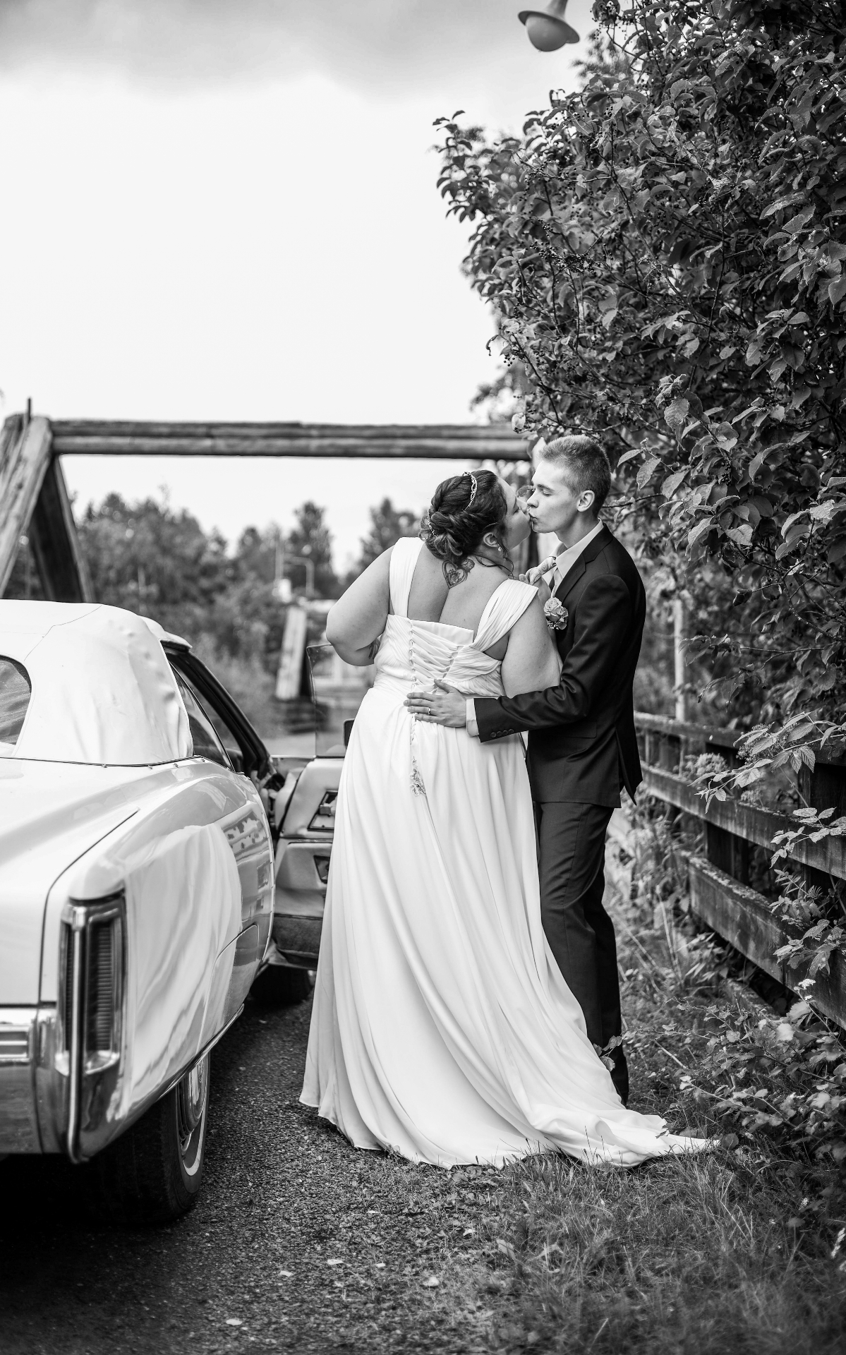 Newlyweds kissing beside a vintage car