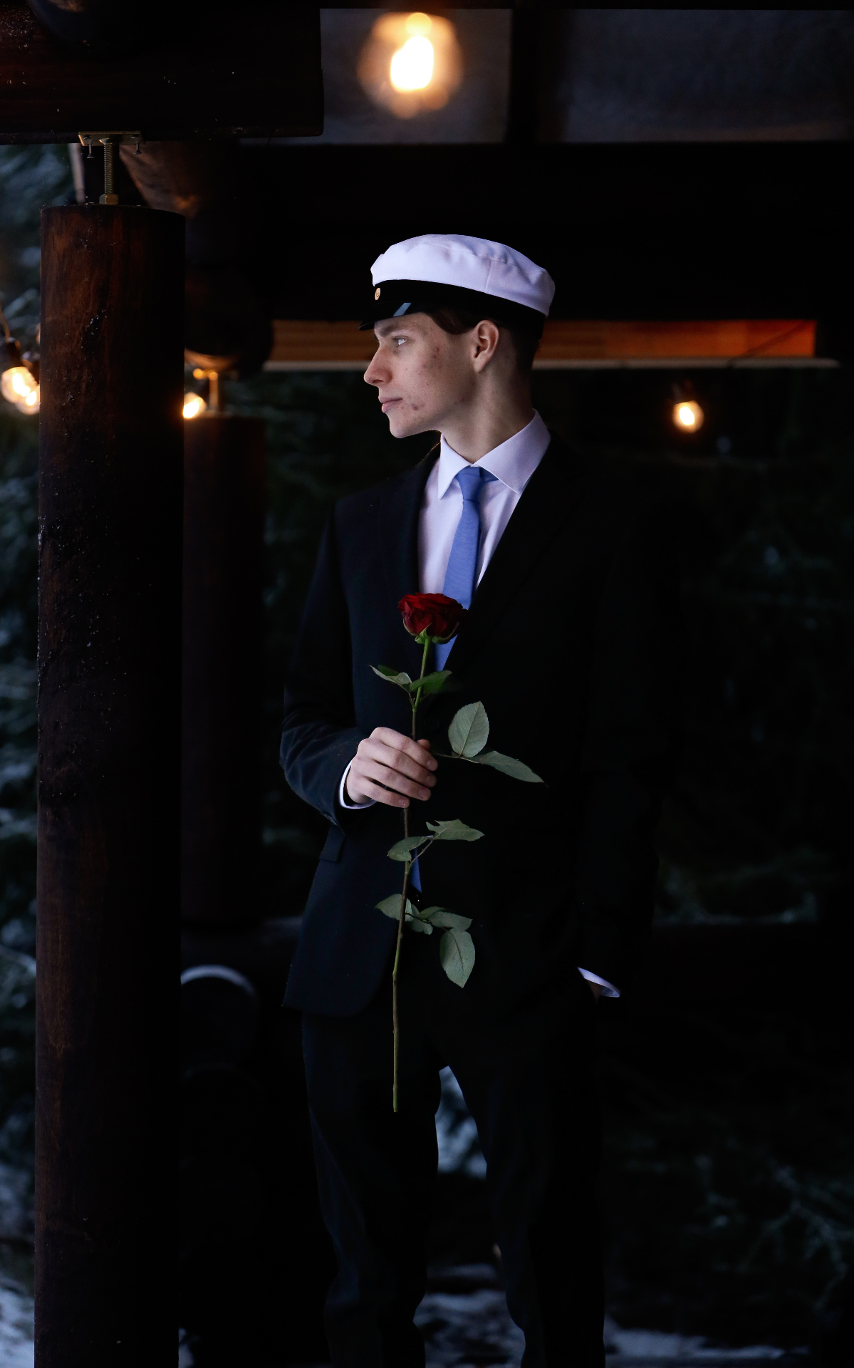 Young man in suit and graduation cap holding a red rose